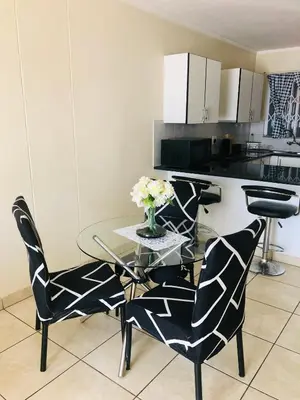 a dining room with a glass table and two chairs at Menlyn Comfort Place in Pretoria