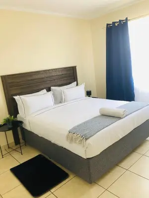 a bedroom with a large bed with a blue curtain at Menlyn Comfort Place in Pretoria
