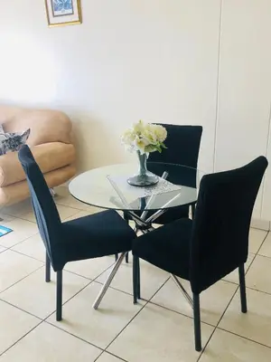 a table with two chairs and a vase with flowers on it at Menlyn Comfort Place in Pretoria