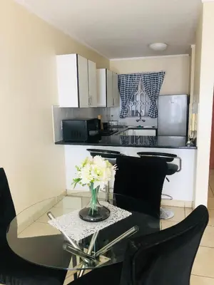 a kitchen with a glass table with a vase of flowers at Menlyn Comfort Place in Pretoria