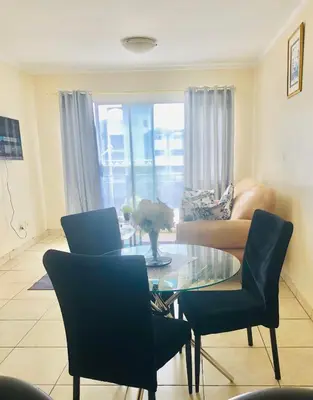 a living room with a glass table and chairs at Menlyn Comfort Place in Pretoria