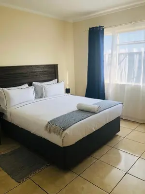 a bedroom with a large bed with a blue curtain at Menlyn Comfort Place in Pretoria
