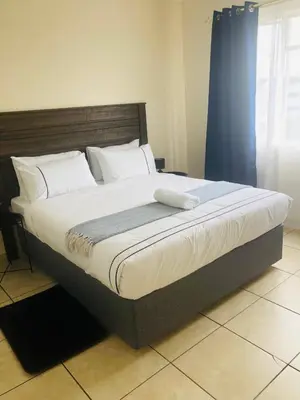 a large bed in a bedroom with a blue curtain at Menlyn Comfort Place in Pretoria