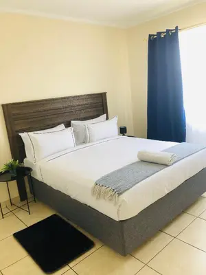a large bed in a bedroom with a blue curtain at Menlyn Comfort Place in Pretoria