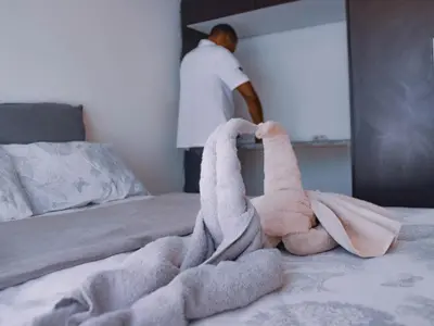 a man standing in a bedroom with a stuffed animal on a bed at Alldays Sunset Lodge in Alldays