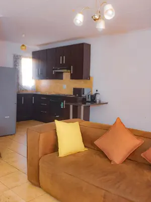 a living room with a brown couch and a kitchen at Alldays Sunset Lodge in Alldays