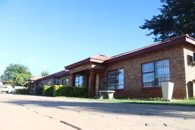 a brick building with windows on a street at Alldays Sunset Lodge in Alldays