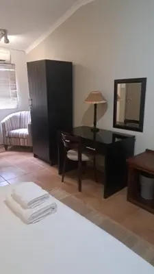 a room with a desk and a chair and a table at The Gateway Inn in Louis Trichardt