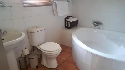 a white bathroom with a toilet and a bath tub at The Gateway Inn in Louis Trichardt