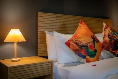 a bed with pillows and a table with a lamp at Ngoma Bush Lodge in Hoedspruit