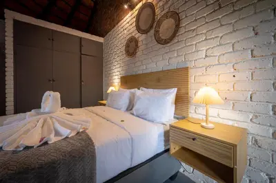 a bedroom with a white bed and a brick wall at Ngoma Bush Lodge in Hoedspruit