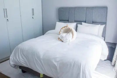 a white cat laying on top of a white bed at Serenity in Hartbeespoort
