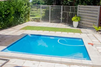 a swimming pool in a garden with a fence at Serenity in Hartbeespoort
