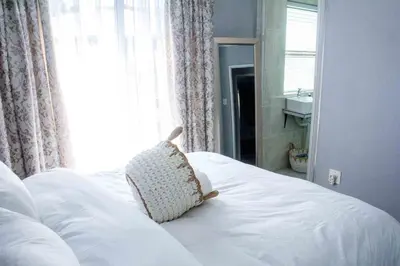 a white bed with a pillow on it in a bedroom at Serenity in Hartbeespoort