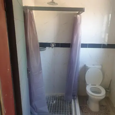 a bathroom with a toilet with a purple shower curtain at Muhle Guesthouse in Giyani