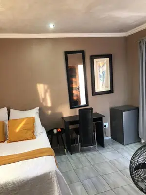 a bedroom with a bed and a desk with a mirror at Muhle Guesthouse in Giyani