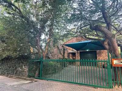 a green fence in front of a building with a tree at Three on Taurus in Nelspruit