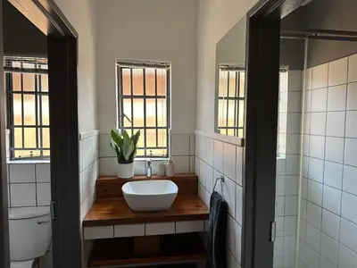 a bathroom with a sink and a toilet and windows at Three on Taurus in Nelspruit