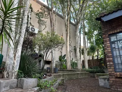 a garden with trees and a brick building at Three on Taurus in Nelspruit