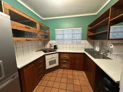 a small kitchen with wooden cabinets and white appliances at Three on Taurus in Nelspruit