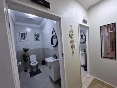 a white bathroom with a toilet and a sink at Nightingale Lodge Bed and Breakfast in Kempton Park