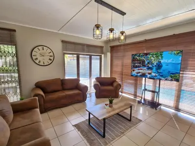 a living room with couches and a table and a clock at Nightingale Lodge Bed and Breakfast in Kempton Park