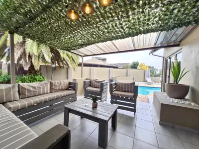 a patio with couches and a table and a pool at Nightingale Lodge Bed and Breakfast in Kempton Park
