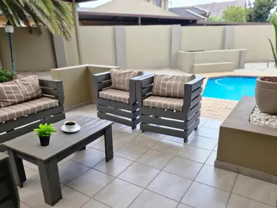 a patio with two chairs and a table and a pool at Nightingale Lodge Bed and Breakfast in Kempton Park