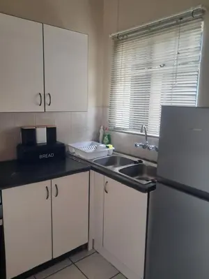 a kitchen with white cabinets and a sink and a refrigerator at Menlyn Place Cityscape in Pretoria