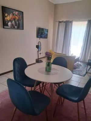 a dining room with a table and blue chairs at Menlyn Place Cityscape in Pretoria