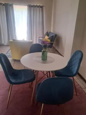 a table with blue chairs and a vase of flowers on it at Menlyn Place Cityscape in Pretoria