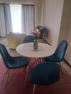 a table with blue chairs and a vase of flowers on it at Menlyn Place Cityscape in Pretoria
