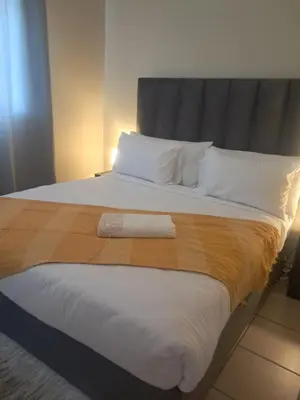 a bedroom with a large bed with a blanket at Menlyn Place Cityscape in Pretoria
