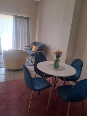 a living room with a table and chairs and a couch at Menlyn Place Cityscape in Pretoria