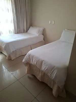 two beds sitting next to a window in a room at The Adress in Midrand