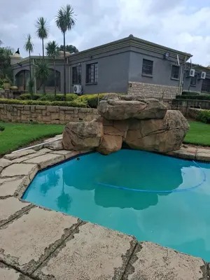 a swimming pool with a rock in front of a house at The Adress in Midrand