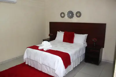 a bedroom with a large bed with a red and white blanket at Phendulani Lodge & Park in Calcutta