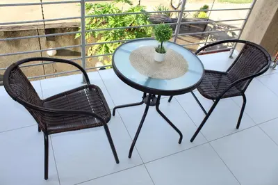 a glass table and two chairs on a balcony at Phendulani Lodge & Park in Calcutta