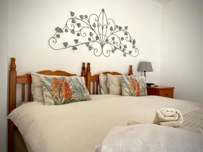 a bedroom with two beds and a chandelier on the wall at La Bella B&B Under The Fig Tree in Bela-Bela
