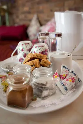 a white plate with cookies and jars on a table at La Bella B&B Under The Fig Tree in Bela-Bela