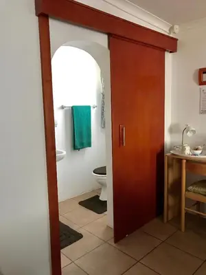 a bathroom with a toilet and a wooden door at La Bella B&B Under The Fig Tree in Bela-Bela