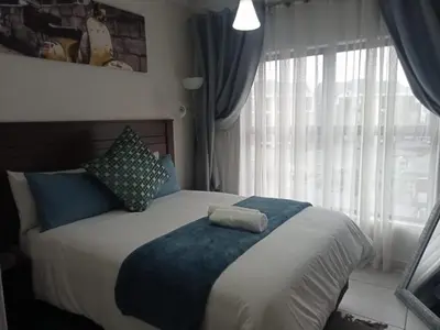 a bedroom with a bed with a blue blanket and a window at Kayalako at The Blyde 2 in Pretoria