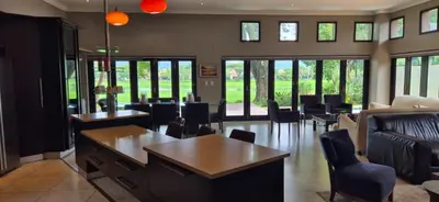 a living room with chairs and tables and windows at Luxury oasis retreat in Hartbeespoort