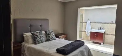a bedroom with a large bed and a sink at Luxury oasis retreat in Hartbeespoort