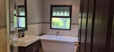 a bathroom with a tub and a sink and two windows at Luxury oasis retreat in Hartbeespoort