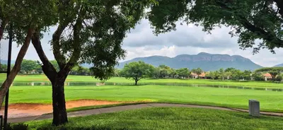 a golf course with a lake and mountains in the background at Luxury oasis retreat in Hartbeespoort