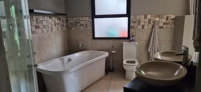 a bathroom with a tub and a toilet and a sink at Luxury oasis retreat in Hartbeespoort