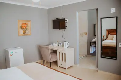 a bedroom with a desk and a bed and a mirror at Karabelo guesthouse in Groblersdal
