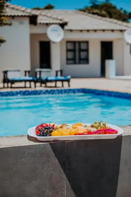 a plate of fruit sitting next to a swimming pool at Karabelo guesthouse in Groblersdal