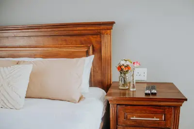 a bed with a wooden headboard and a table with flowers at Karabelo guesthouse in Groblersdal